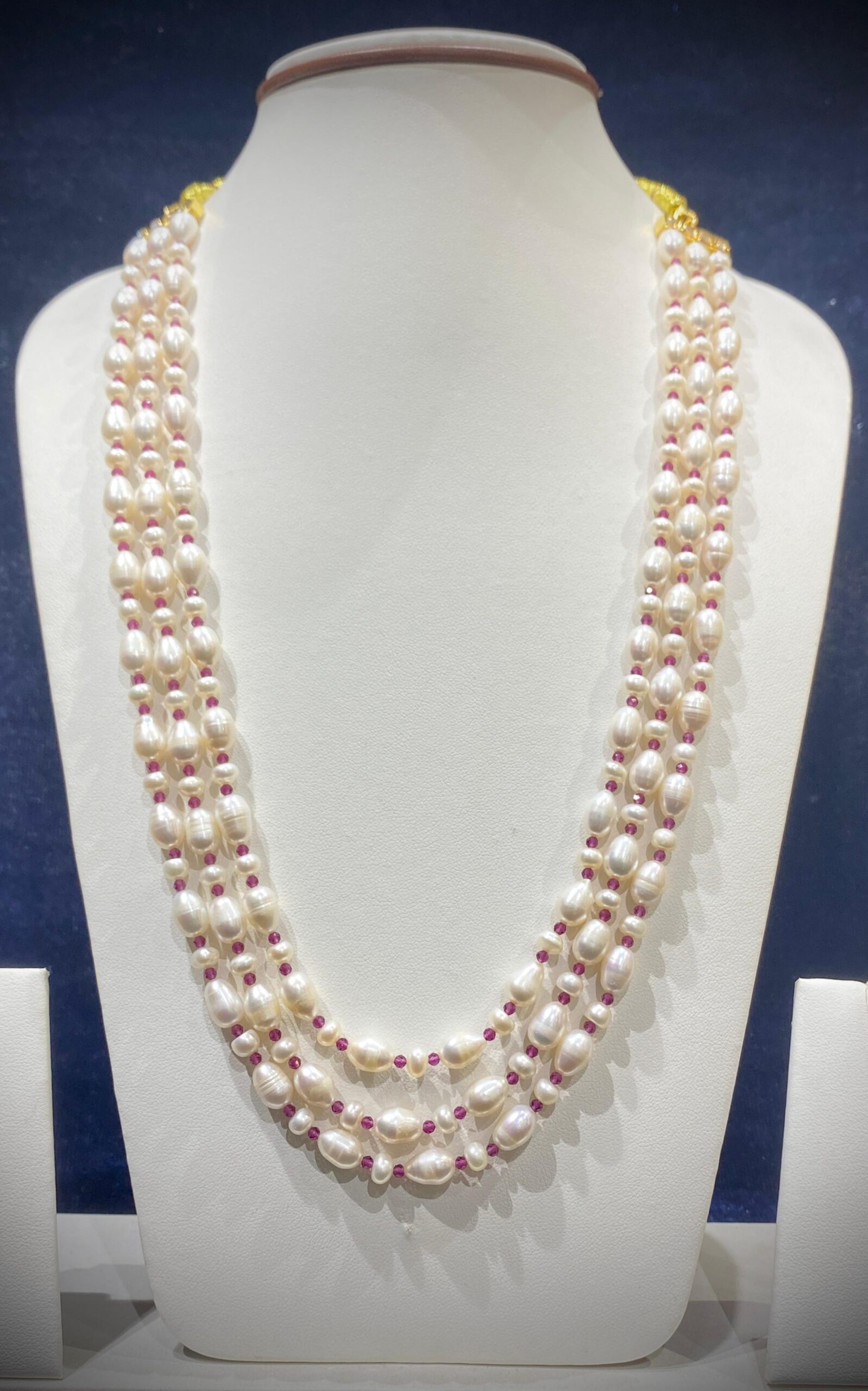 Three-Strand Pearl and Ruby Necklace with a luxurious blend of pearls and rubies for a regal look.